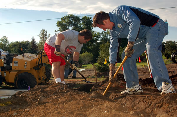 Travis Gause (left) and Jason lower the irrigation trench to the correct level